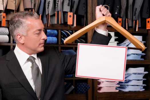 Businessman holding a hanger with blank signboard in a clothing store