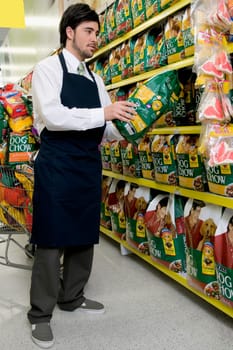 Sales clerk holding dog food in a supermarket