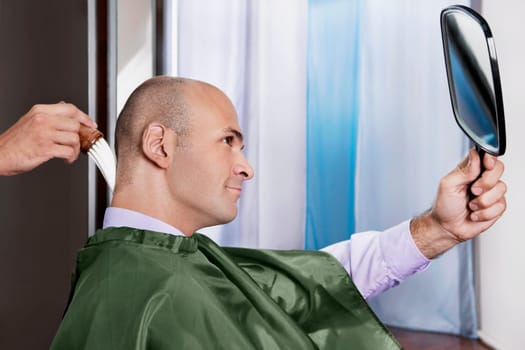 Man looking himself in a mirror after a haircut