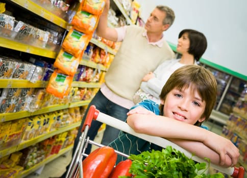 Portrait of a boy in a supermarket with his parents shopping behind him
