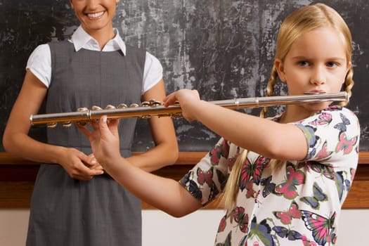 Schoolgirl playing a flute in a classroom