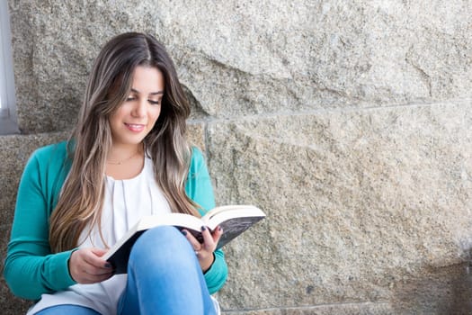 Beautiful young woman relaxing at home reading a book