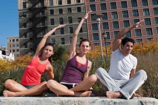 Man exercising with two women on a rock