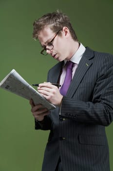 Close_up of a businessman marking on a newspaper