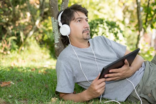 Young man relaxing with a tablet computer at a garden