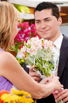 Female florist giving a bouquet of flowers to a customer