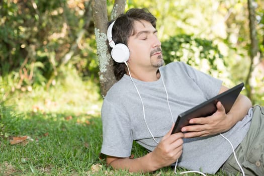 Young man relaxing with a tablet computer at a garden