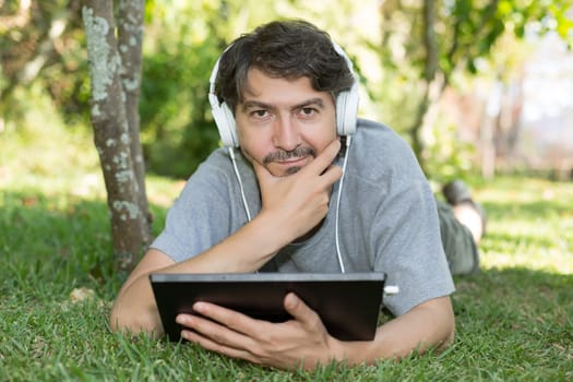 Young man relaxing with a tablet computer at a garden
