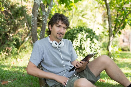 Young man relaxing with a tablet computer at a garden