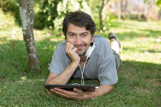 Young man relaxing with a tablet computer at a garden