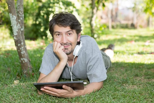 Young man relaxing with a tablet computer at a garden