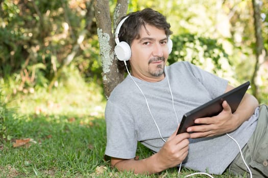Young man relaxing with a tablet computer at a garden