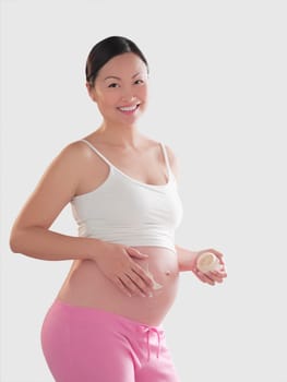 Pregnant woman applying moisturizer on her abdomen