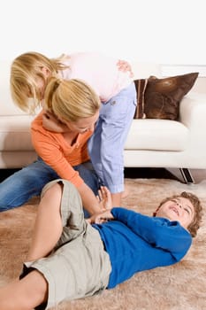 Woman playing with her son and a daughter in a living room