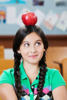 Schoolgirl carrying an apple on her head in a classroom