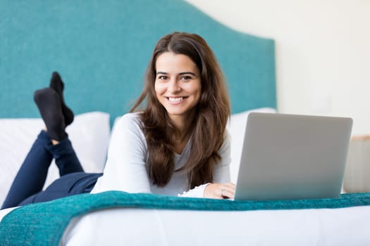 Beautiful young woman relaxing at home on her laptop computer