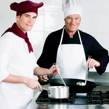 Two chefs cooking food in the kitchen