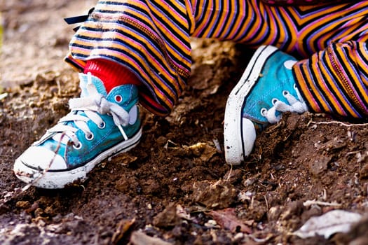 Low section view of a child sitting in dirt