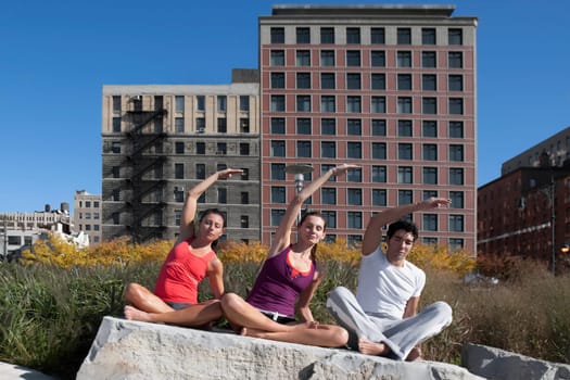 Man exercising with two women on a rock