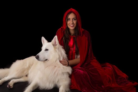 Woman wearing a red hood posing in studio with her dog