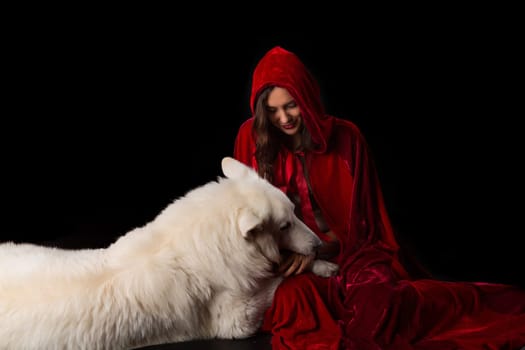 Woman wearing a red hood posing in studio with her dog