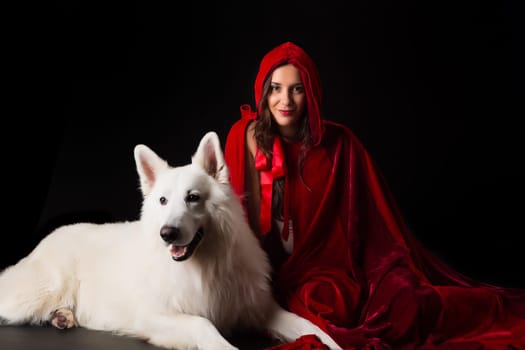 Woman wearing a red hood posing in studio with her dog