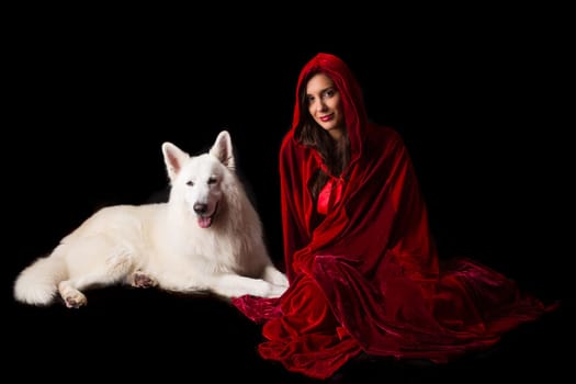 Woman wearing a red hood posing in studio with her dog
