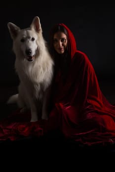 Woman wearing a red hood posing in studio with her dog