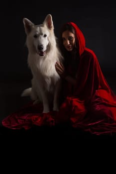 Woman wearing a red hood posing in studio with her dog