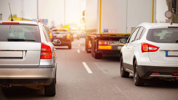 Line od cars waiting in traffic jam in rush hour. Automobiles with brake lights on stucked on highway in a city. Vehicles travelling on crowded road.