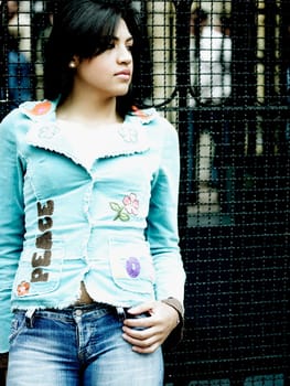Close_up of a young woman leaning against a grille