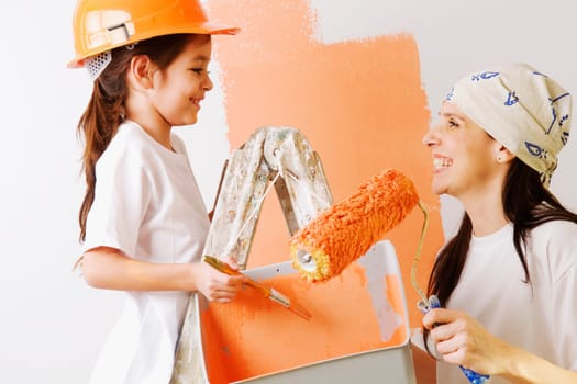 Close_up of a mature woman and her daughter painting a wall