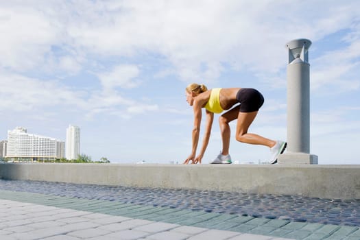 Side profile of a mid adult woman in a running position on the ledge