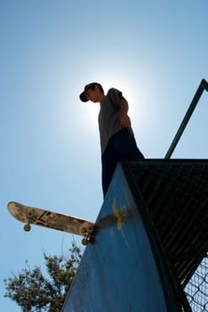 Low angle view of a young male skateboarder standing on a stunt ramp