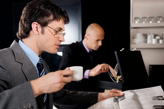 Businessman holding a cup of tea and reading a newspaper