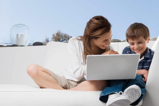 Mid adult woman smiling with her son in front of a laptop