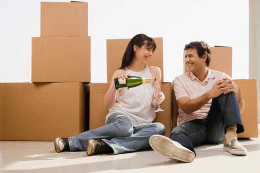 Mature woman pouring champagne into champagne flute beside a mid adult man