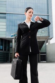 Businesswoman holding a bag and checking the time
