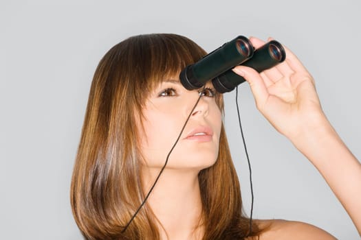 Close_up of a young woman looking through a pair of binoculars