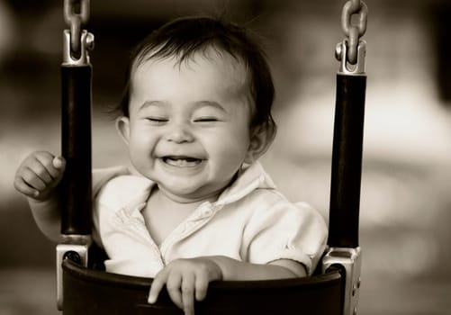 Close_up of a baby girl sitting in a swing and smiling