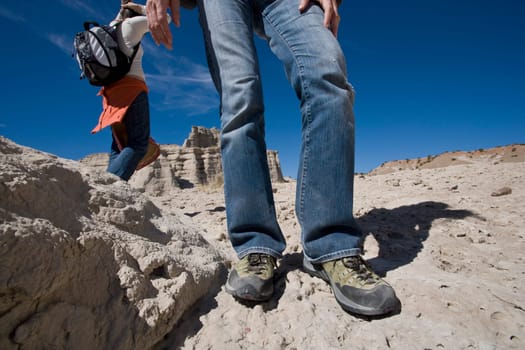 Low section view of a man standing on eroded rocks with a woman walking in the background