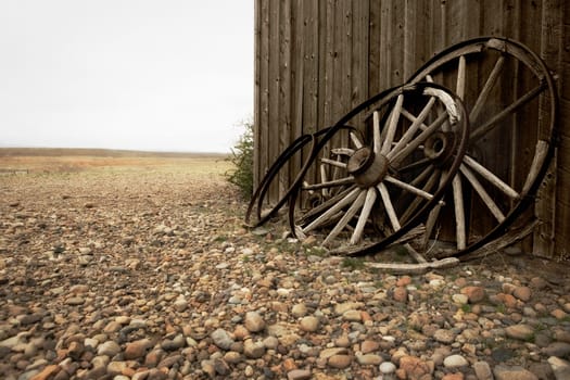 Wagon wheels leaning against the wall of an abandoned building, Old Trail Town, Cody, Wyoming, USA