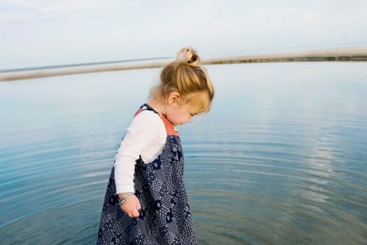 Side profile of a baby girl standing in water