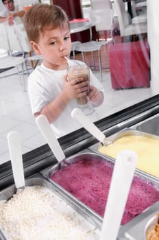 Boy looking at ice creams while drinking milkshake