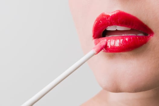 Close_up of a young woman applying lipstick