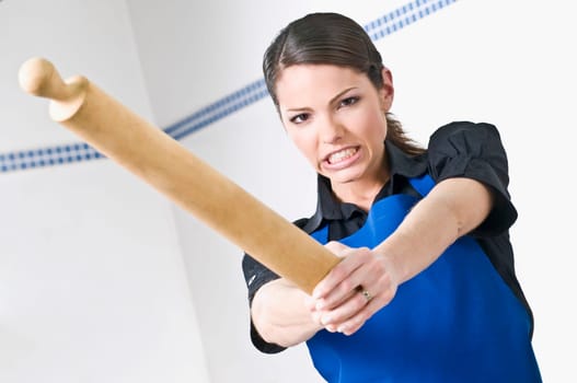 Portrait of a female chef holding a rolling pin and clenching her teeth