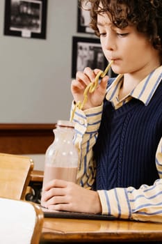 Schoolboy drinking chocolate milkshake in a classroom