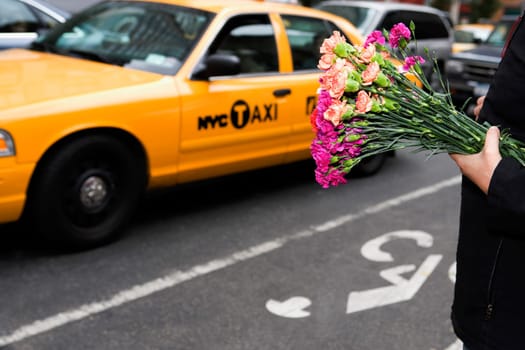 Man holding bunch of flowers in a market, 28 Street, New York City, New York State, USA