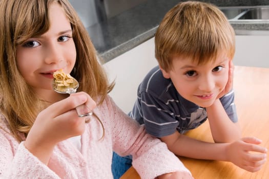 Portrait of a girl having breakfast beside her brother