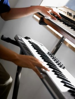Close-up of a person's hands playing two electric pianos
